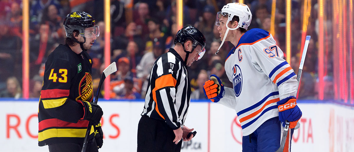 Quinn Hughes #43 of the Vancouver Canucks and Connor McDavid #97 of the Edmonton Oilers talk with Referee Kelly Sutherland #11 of their NHL game at Rogers Arena on November 6, 2023 in Vancouver, British Columbia, Canada.
