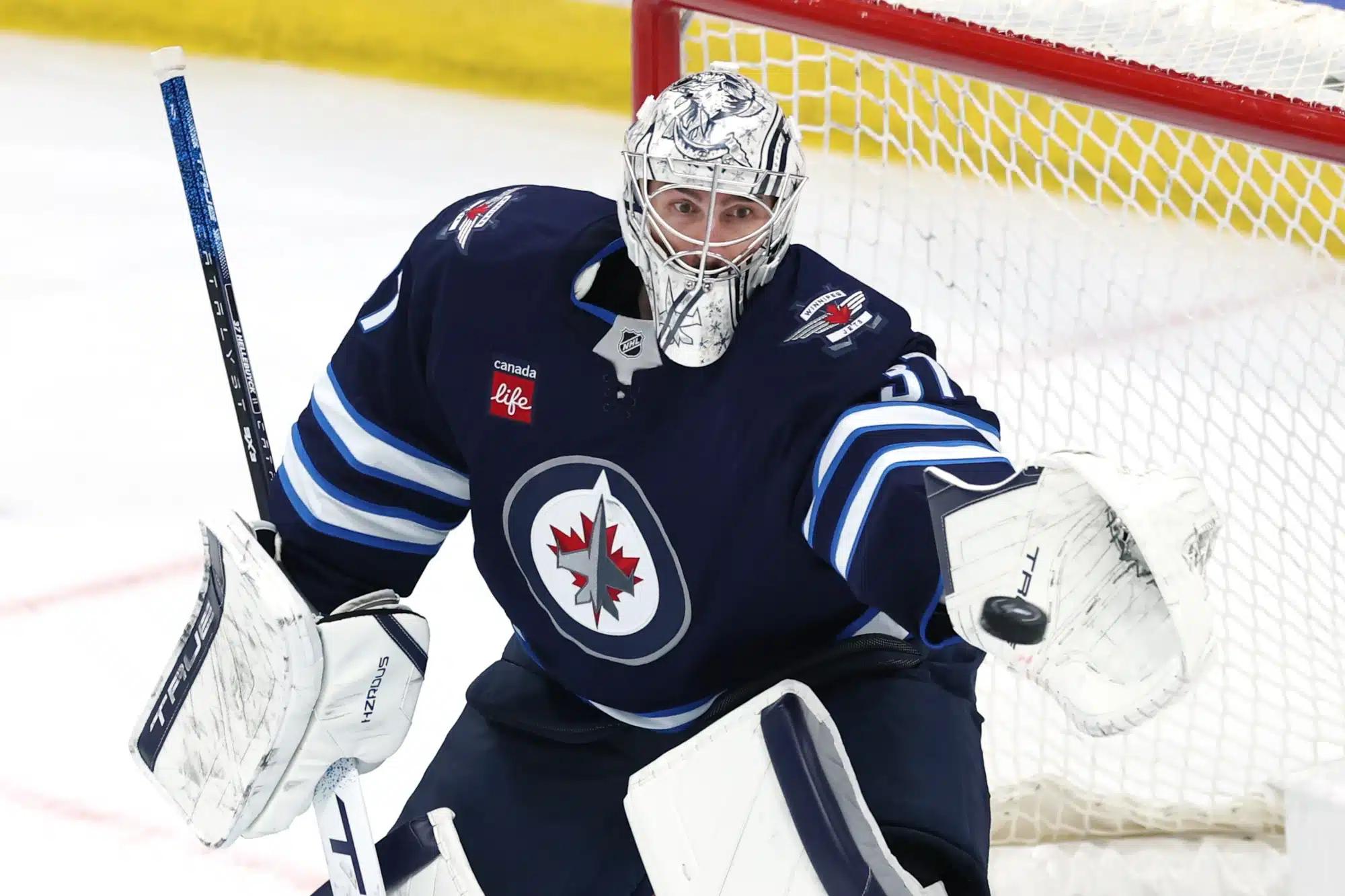 Apr 21, 2025; Winnipeg, Manitoba, CAN; Winnipeg Jets goaltender Connor Hellebuyck (37) makes a glove save against the St. Louis Blues in the third period in game two of the first round of the 2025 Stanley Cup Playoffs at Canada Life Centre.