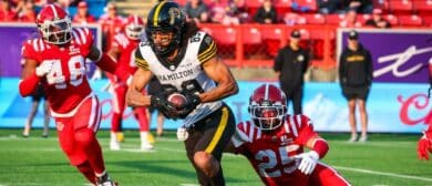 Hamilton Tiger-Cats wide receiver Kenny Lawler (89) runs with the ball under pressure from Calgary Stampeders defensive back Jaydon Grant (25) during the second half at McMahon Stadium.