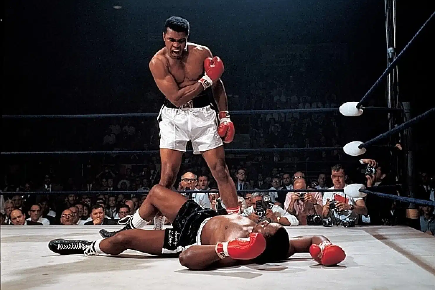 Mohamed Ali in a boxing ring standing over his opponent