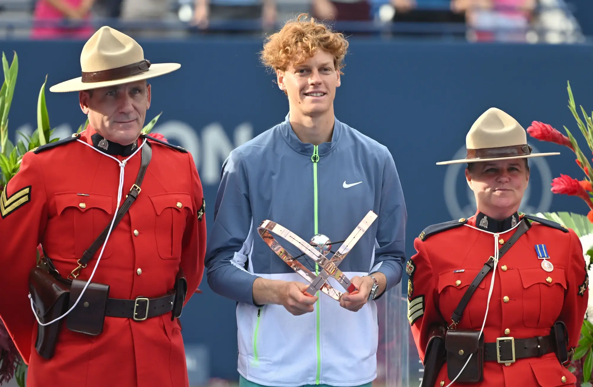 Aug 12, 2023; Toronto, Ontario, Canada; Jannik Sinner (ITA) poses with the winner's trophy between two Canadian RCMP Mounties after defeating Alex De Minaur (AUS) (not pictured) in final round play at Sobeys Stadium.