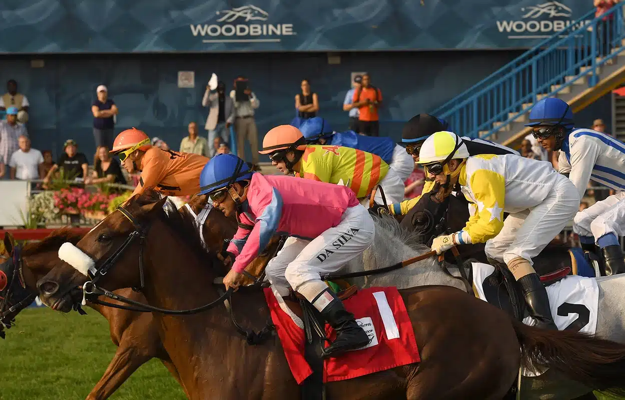 A close up photo of horses and jockeys racing at the 134th Breeders' Stakes at Woodbine.