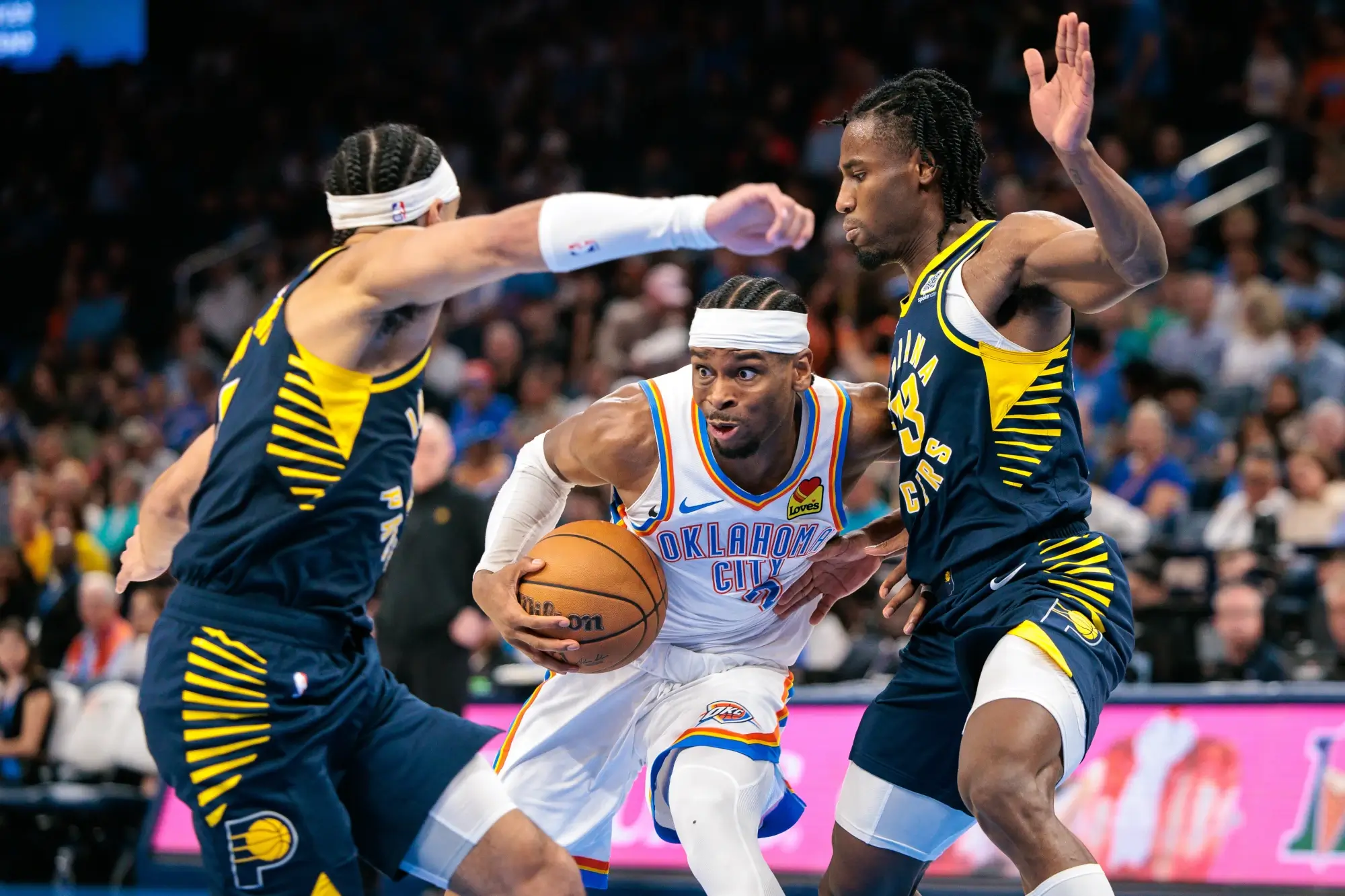 Shai gilgeous-alexander battles against two defenders in an NBA playoff game in 2025.
