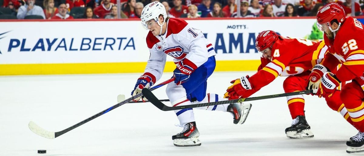 Montreal Canadiens right wing Cole Caufield (13) controls the puck against Calgary Flames defenseman Joel Hanley (44) and defenseman MacKenzie Weegar (52) during the third period at Scotiabank Saddledome