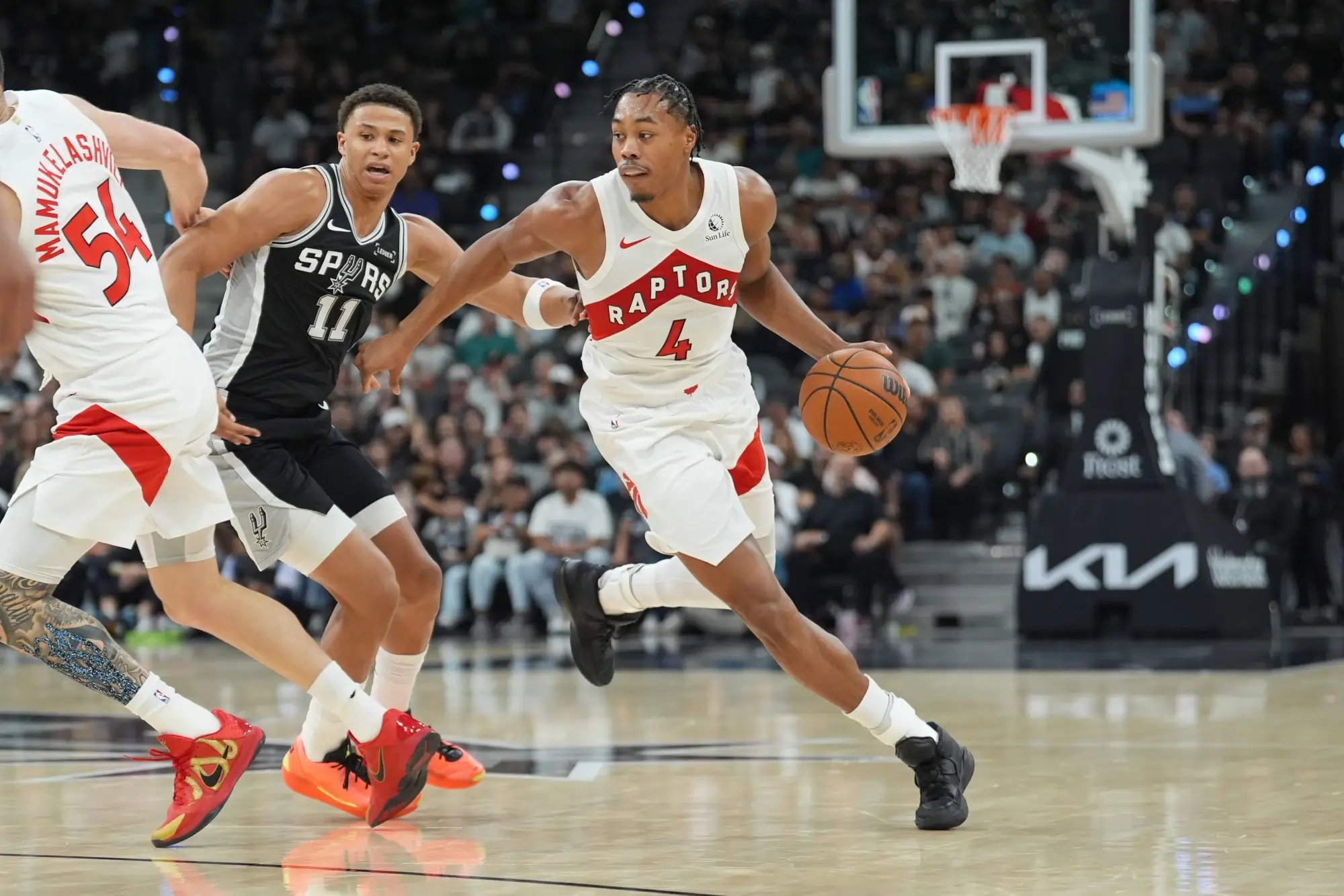 Oct 27, 2025; San Antonio, Texas, USA; Toronto Raptors forward/guard Scottie Barnes (4) dribbles past San Antonio Spurs forward Carter Bryant (11) in the first half at Frost Bank Center.