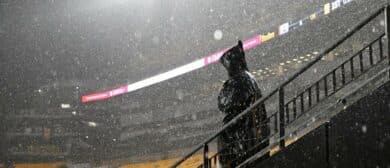 A fan stands in the rain during a weather delay before the game between the Pittsburgh Steelers and Dallas Cowboys at Acrisure Stadium.