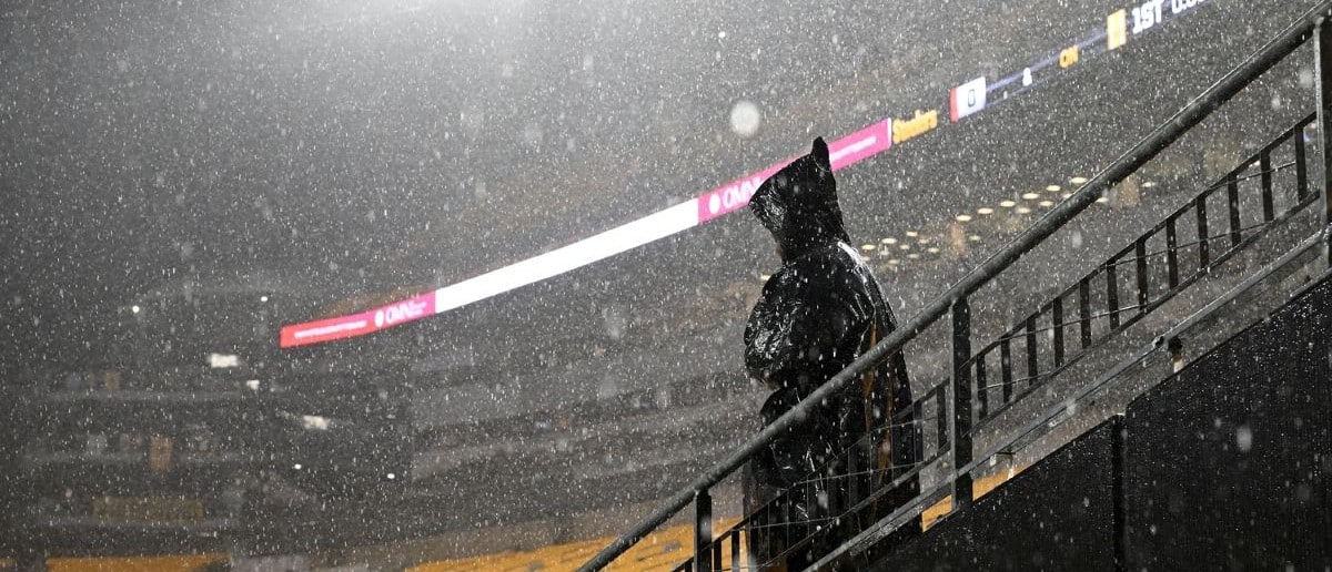 A fan stands in the rain during a weather delay before the game between the Pittsburgh Steelers and Dallas Cowboys at Acrisure Stadium.