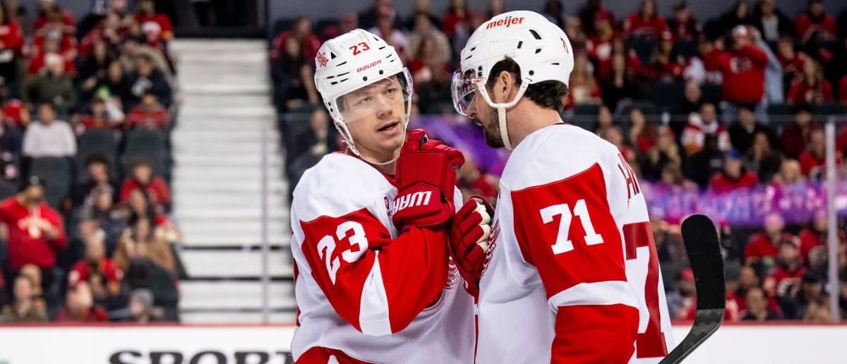 Detroit Red Wings left wing Lucas Raymond (23) and center Dylan Larkin (71) talk strategy before a face-off against the Calgary Flames during the third period at Scotiabank Saddledome
