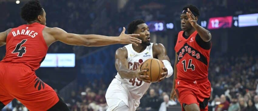 Cleveland Cavaliers guard Donovan Mitchell (45) drives between Toronto Raptors forward Scottie Barnes (4) and guard Ja'Kobe Walter (14) in the first quarter at Rocket Arena.