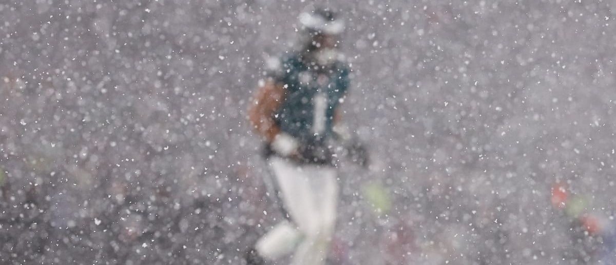 Philadelphia Eagles quarterback Jalen Hurts (1) is obscured by snow before a play against the Los Angeles Rams in a 2025 NFC divisional round game at Lincoln Financial Field.