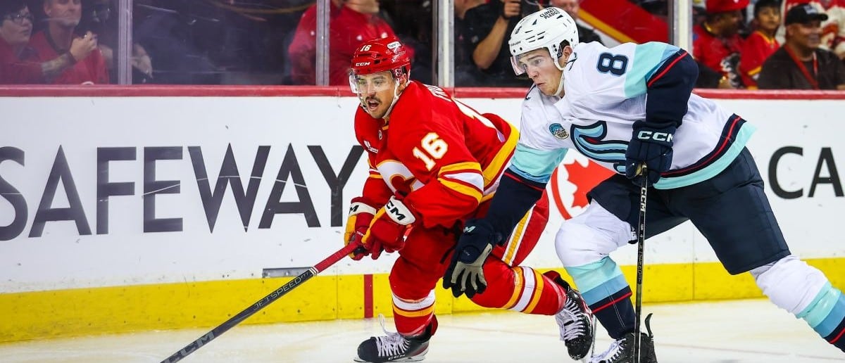 Calgary Flames center Morgan Frost (16) and Seattle Kraken defenseman Cale Fleury (8) battles for the puck during the second period at Scotiabank Saddledome
