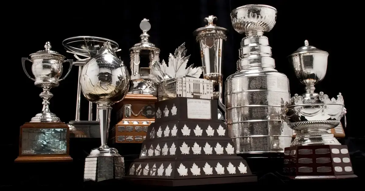 A view of multiple NHL Award trophies against a black background.