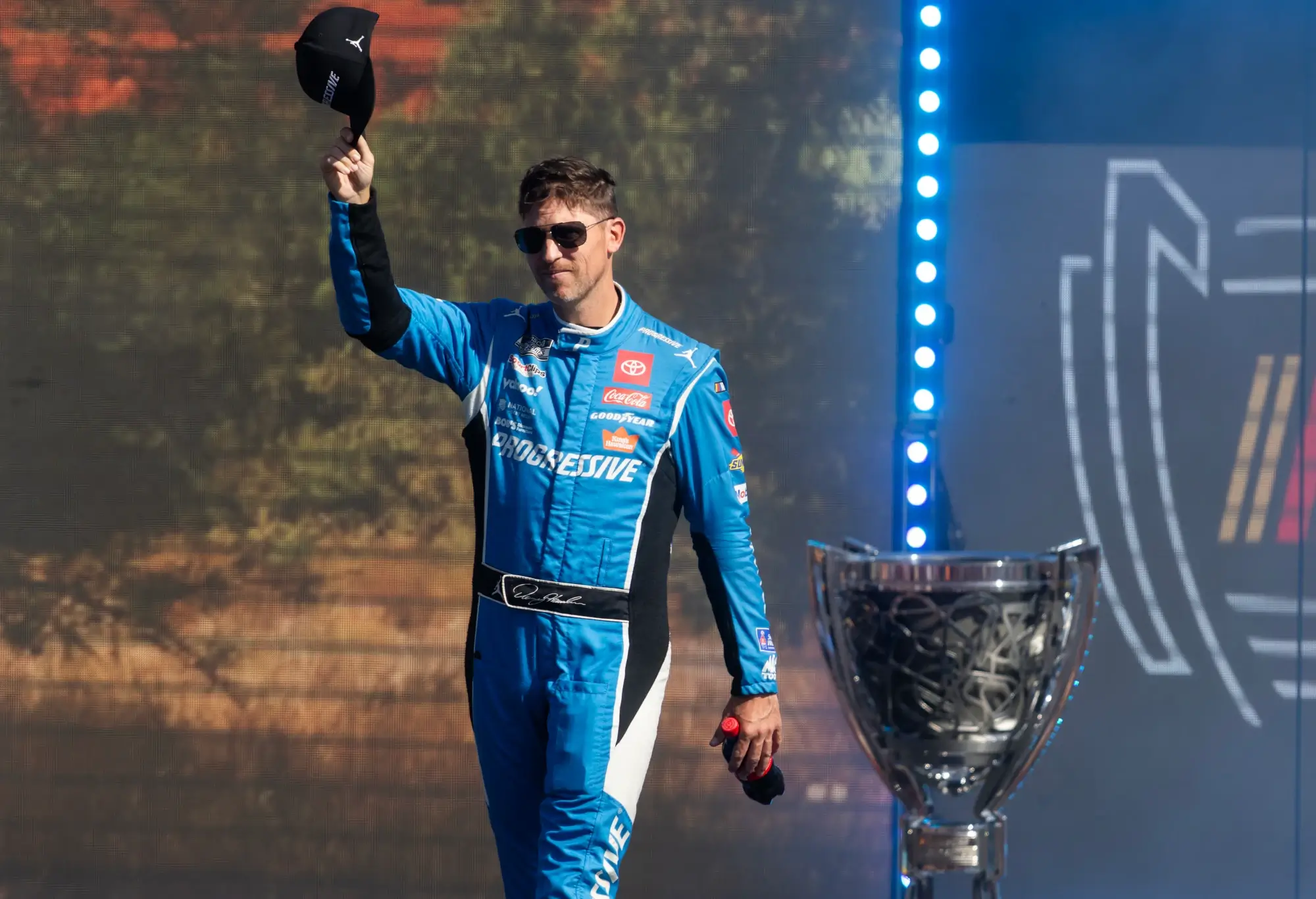 Nov 2, 2025; Avondale, Arizona, USA; NASCAR Cup Series driver Denny Hamlin walks by the championship trophy as he introduced prior to the NASCAR Championship race at Phoenix Raceway.