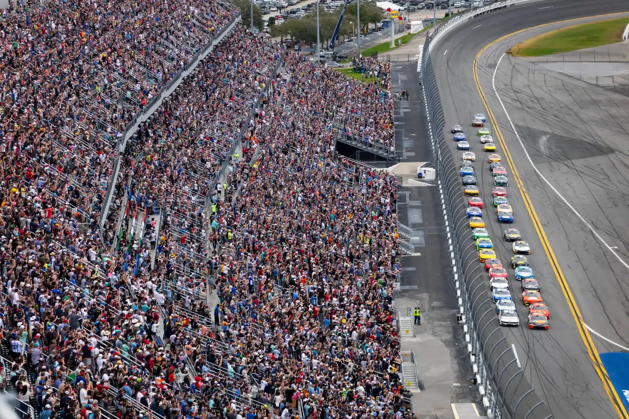 Feb 16, 2025; Daytona Beach, Florida, USA; The sold out crowd of fans in the grandstands look on as NASCAR Cup Series driver Austin Cindric (2) and driver Chase Briscoe (19) lead the field at the green flag to begin the Daytona 500 at Daytona International Speedway.
