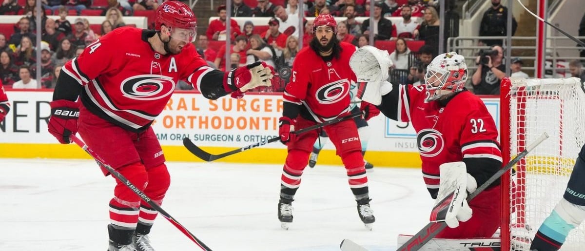 Carolina Hurricanes defenseman Jaccob Slavin (74) and Carolina Hurricanes goaltender Brandon Bussi (32) reach for the puck against the Seattle Kraken during the second period at Lenovo Center