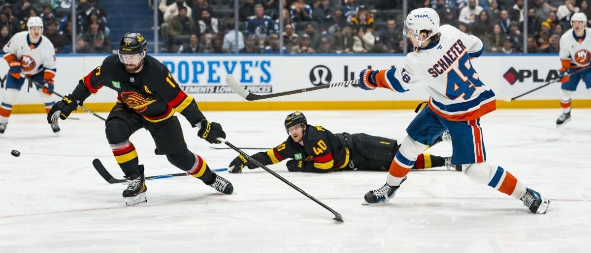 New York Islanders defenseman Matthew Schaefer (48) shoots the puck against Vancouver Canucks defenseman Filip Hronek (17) and center Elias Pettersson (40) in the third period at Rogers Arena.