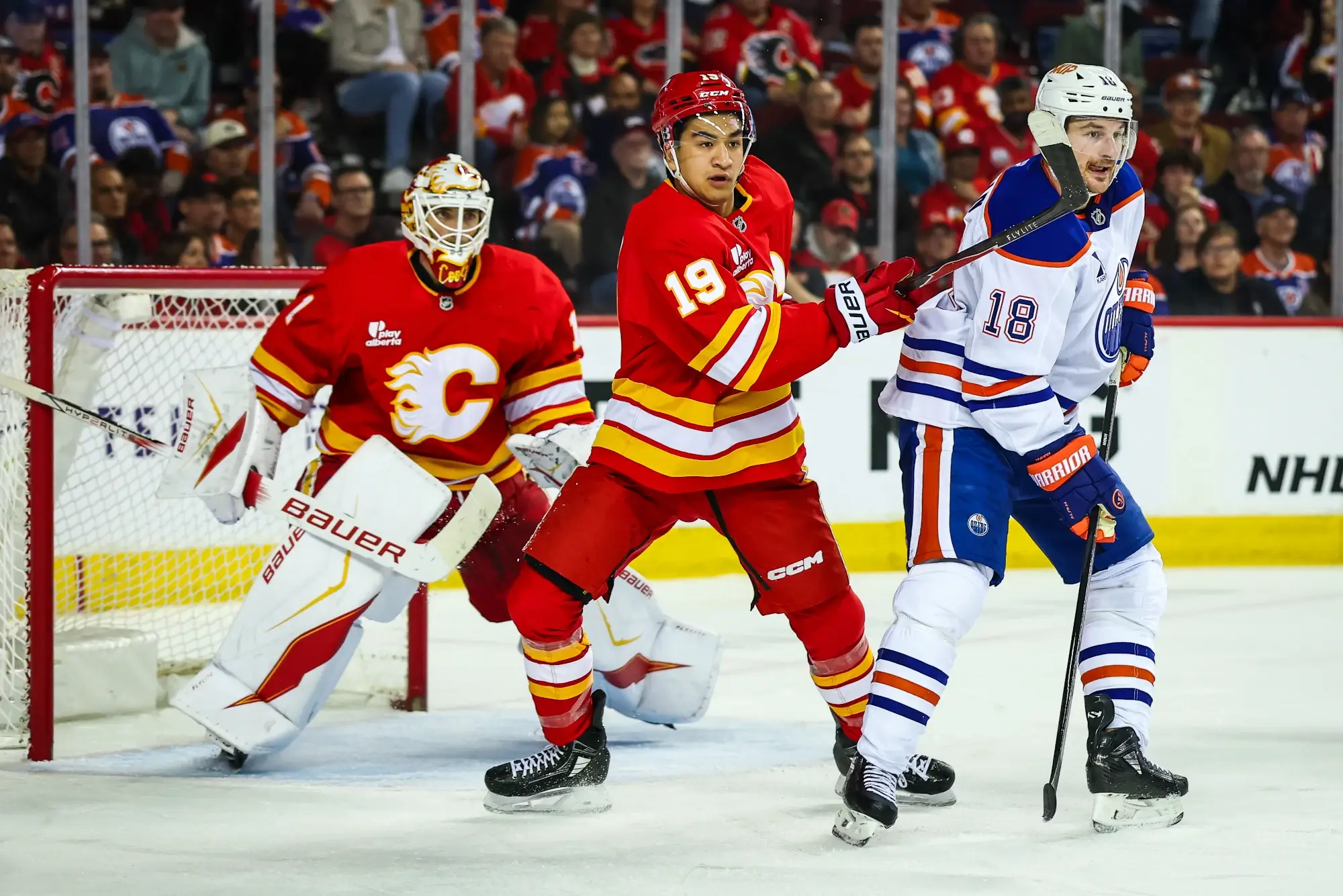 Feb 4, 2026; Calgary, Alberta, CAN; Calgary Flames defenseman Zayne Parekh (19) and Edmonton Oilers left wing Zach Hyman (18) fight for position in front of Calgary Flames goaltender Devin Cooley (1) during the third period at Scotiabank Saddledome. 