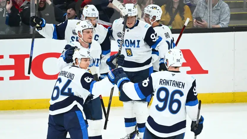 Team Finland men's hockey team celebrating a goal on the ice.