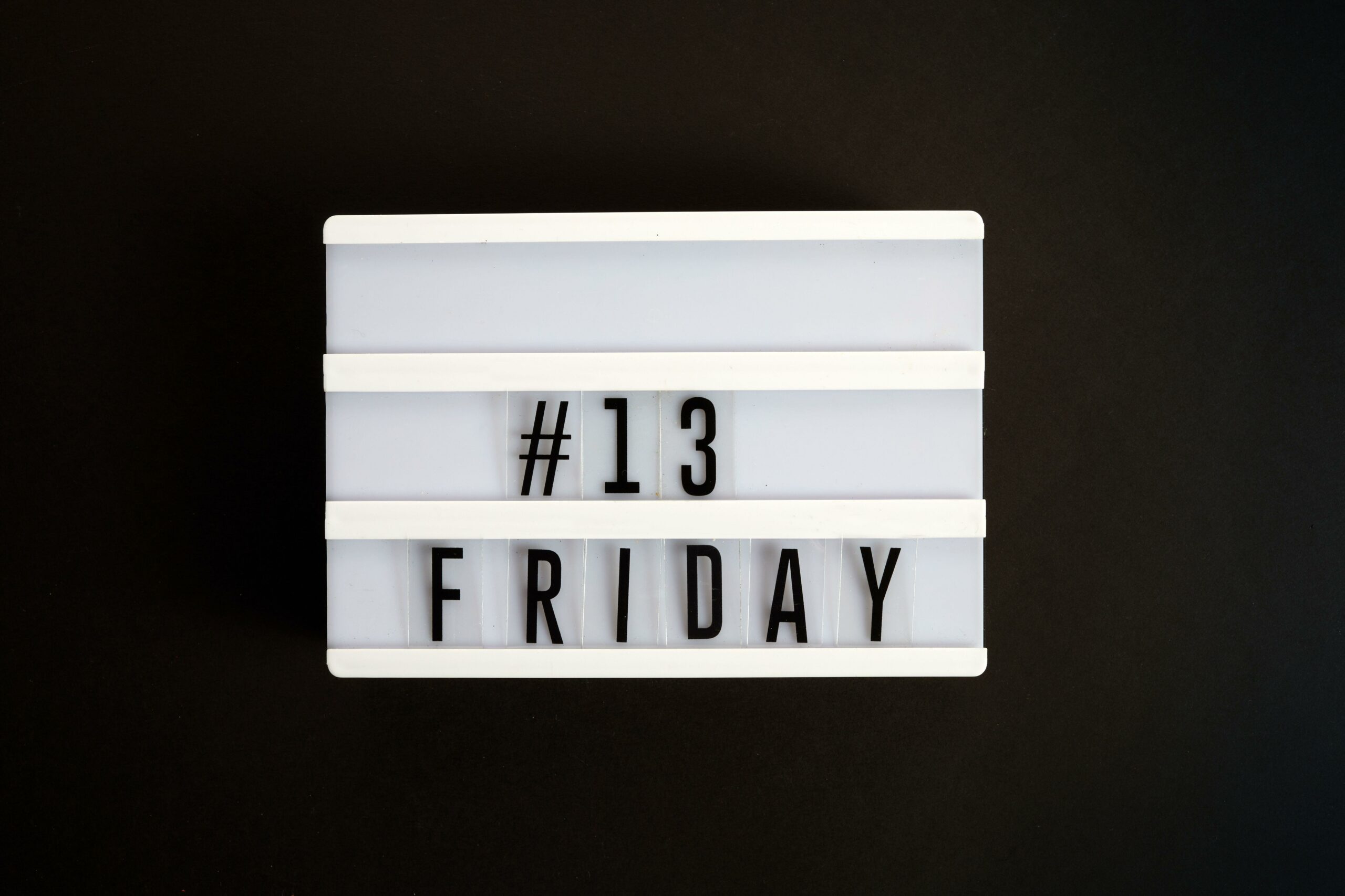 Lightbox sign displaying “#13 Friday” on a black background, symbolizing Friday the 13th superstition.
