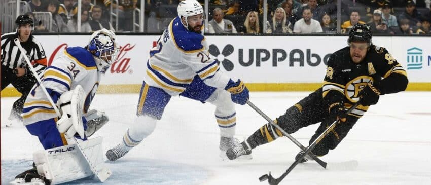 Boston Bruins right wing David Pastrnak (88) gets off a shot on Buffalo Sabres goaltender Alex Lyon (34) as defenseman Conor Timmins (21) defends during the first period at TD Garden