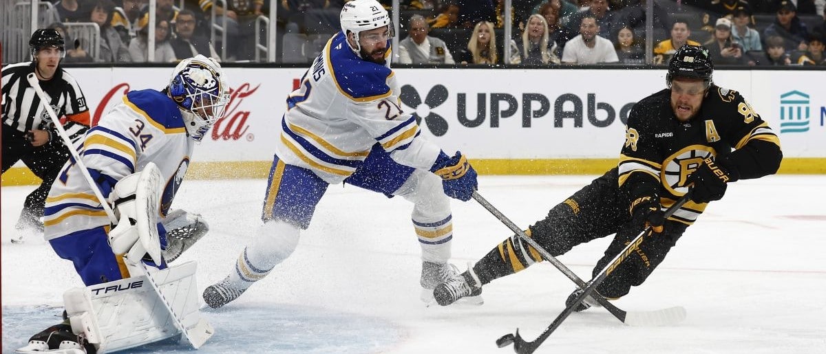 Boston Bruins right wing David Pastrnak (88) gets off a shot on Buffalo Sabres goaltender Alex Lyon (34) as defenseman Conor Timmins (21) defends during the first period at TD Garden