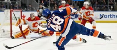 New York Islanders defenseman Matthew Schaefer (48) attempts a shot and Calgary Flames goaltender Dustin Wolf (32) makes a the save during the second period at UBS Arena