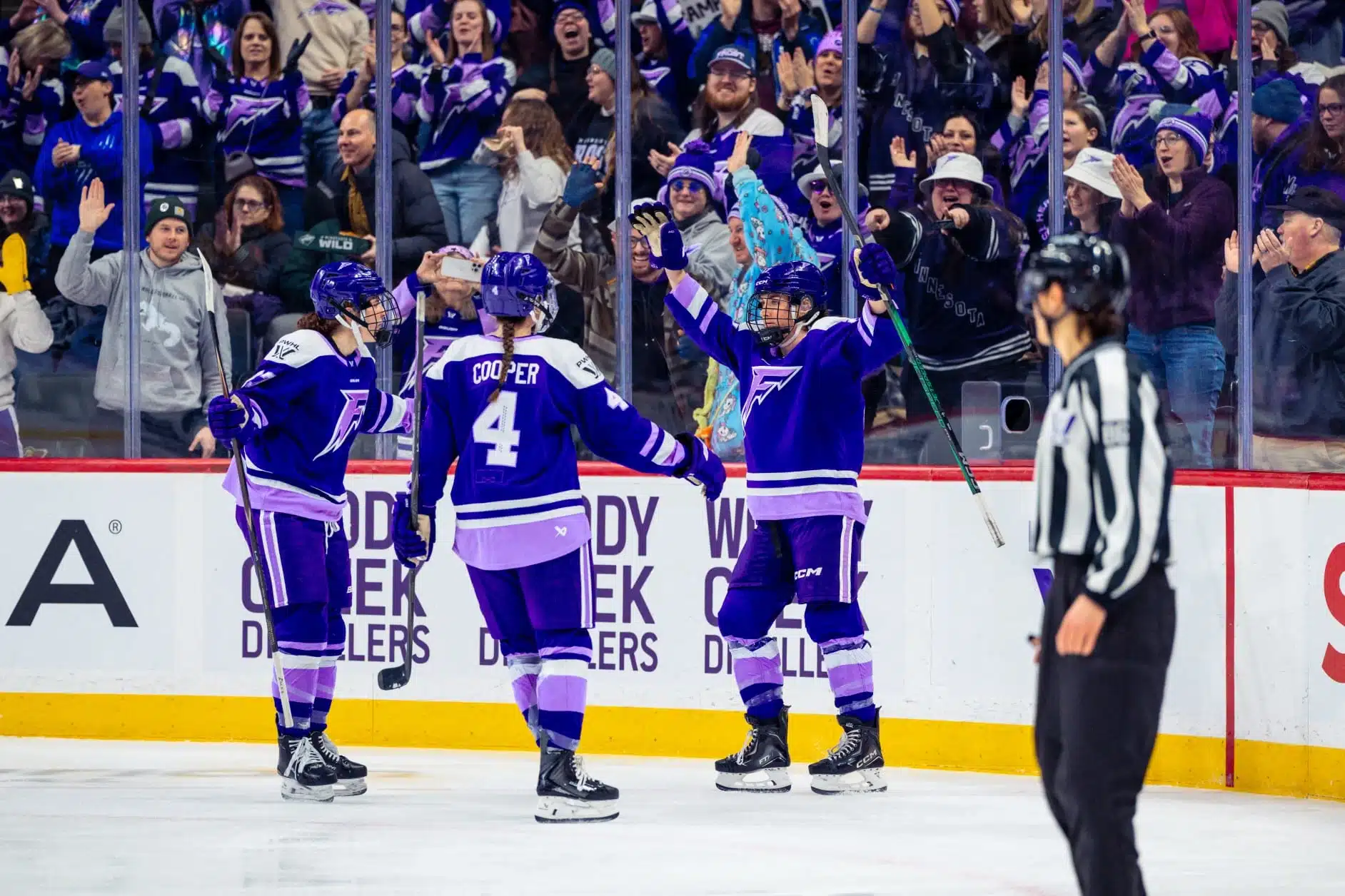 Minnesota Frost teammates celebrate together on the ice during a PWHL game.