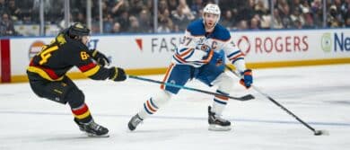 Vancouver Canucks forward David Kampf (64) stick checks Edmonton Oilers forward Connor McDavid (97) in the third period at Rogers Arena