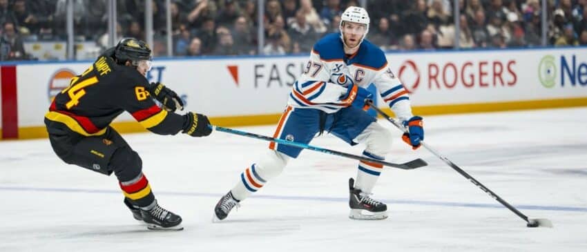 Vancouver Canucks forward David Kampf (64) stick checks Edmonton Oilers forward Connor McDavid (97) in the third period at Rogers Arena