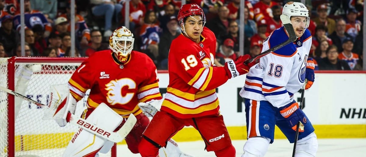 Calgary Flames defenseman Zayne Parekh (19) and Edmonton Oilers left wing Zach Hyman (18) fight for position in front of Calgary Flames goaltender Devin Cooley (1) during the third period at Scotiabank Saddledome