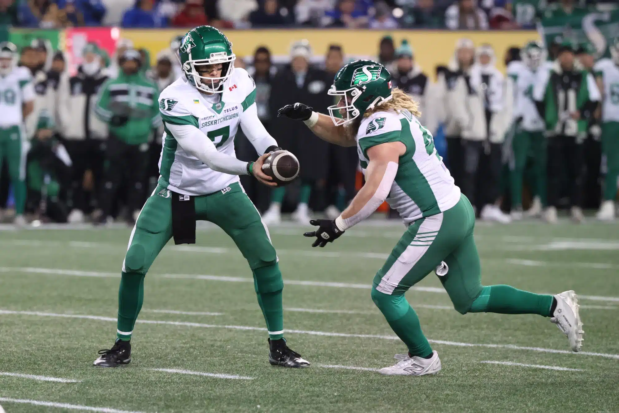 Nov 16, 2025; Winnipeg, Manitoba, Canada; Saskatchewan Roughriders quarterback Trevor Harris (7) hands off the ball to running back A.J. Ouellette (45) during the second quarter against the Montreal Alouettes during the 112th Grey Cup Championship at Princess Auto Stadium.