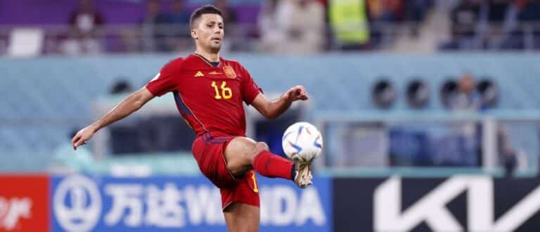Spain midfielder Rodri (16) kicks the ball against Japan during the second half of a group stage match during the 2022 World Cup at Khalifa International Stadium.