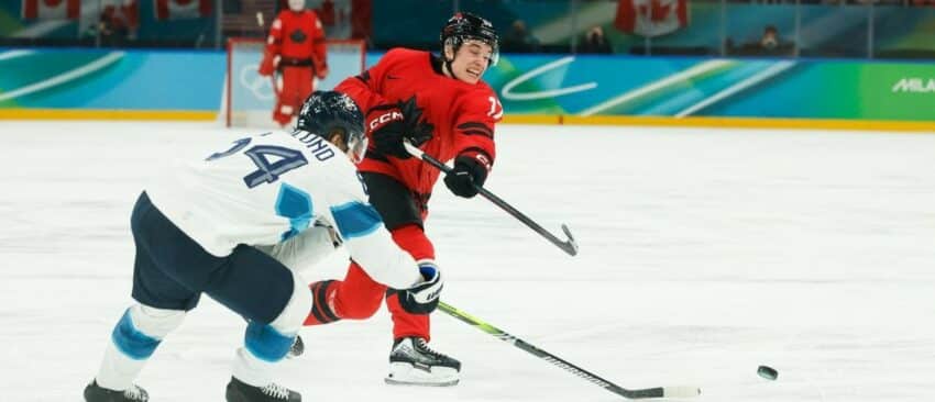 Macklin Celebrini (17) of Canada takes a shot as Mikael Granlund (64) of Finland defends during the third period in a men's ice hockey semifinal during the Milano Cortina 2026 Olympic Winter Games at Milano Santagiulia Ice Hockey Arena