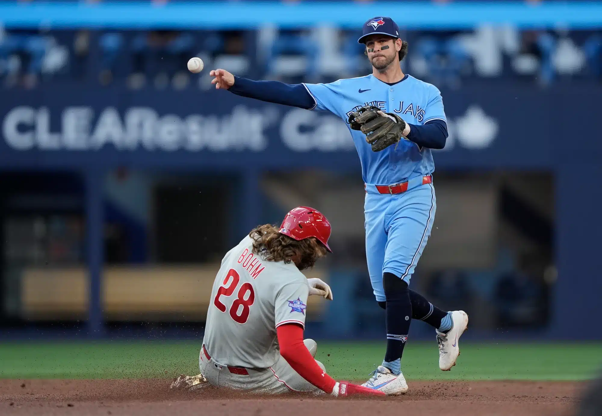 Jun 8, 2026; Toronto, Ontario, CAN; Toronto Blue Jays second baseman Ernie Clement (22) turns a double play at second base against Philadelphia Phillies third baseman Alec Bohm (28) and catcher J.T. Realmuto (10) during the second inning at Rogers Centre.