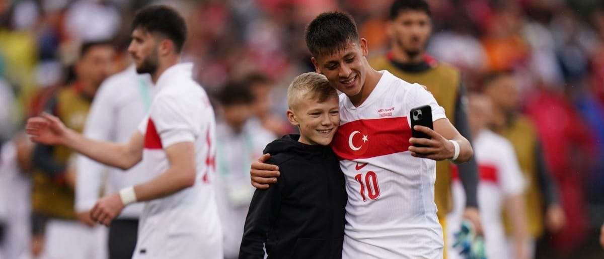A soccer fan runs onto the field to get a photo with Turkey forward Arda Güler (10) after the game against team USA in the second half at Pratt & Whitney Stadium at Rentschler Field