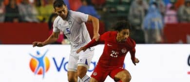Team Canada midfielder Nathan Saliba (25) carries the ball in front of Uzbekistan defender Rustam Ashurmatov (5) /during the second half at Commonwealth Stadium