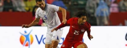 Team Canada midfielder Nathan Saliba (25) carries the ball in front of Uzbekistan defender Rustam Ashurmatov (5) /during the second half at Commonwealth Stadium