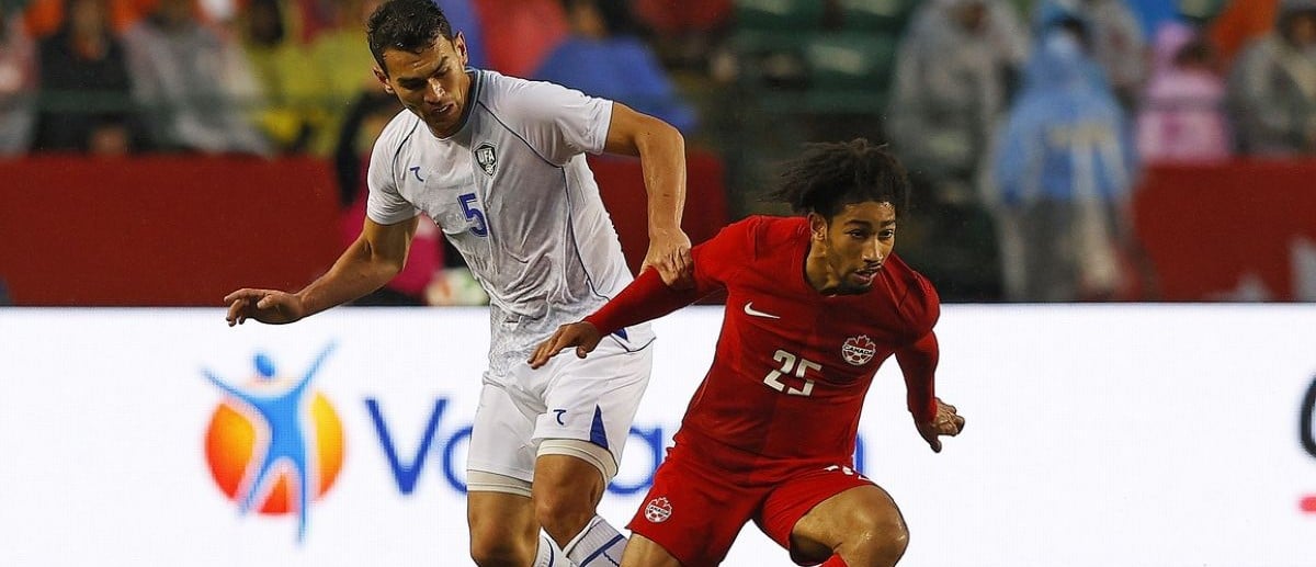 Team Canada midfielder Nathan Saliba (25) carries the ball in front of Uzbekistan defender Rustam Ashurmatov (5) /during the second half at Commonwealth Stadium