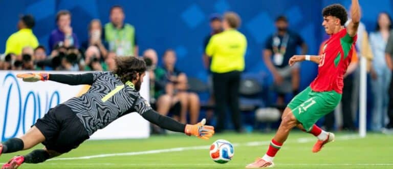 Brazil goalkeeper Alisson Becker (1) looks to block a shot by Morocco forward Ayoube Amaimouni-Echghouyab (21) during a FIFA World Cup Group C match between Brazil and Morocco at New York New Jersey Stadium on Saturday, June 13, 2026, in East Rutherford, New Jersey.