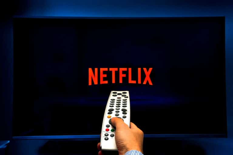 Male hand holding a remote control while watching Netflix on a TV screen