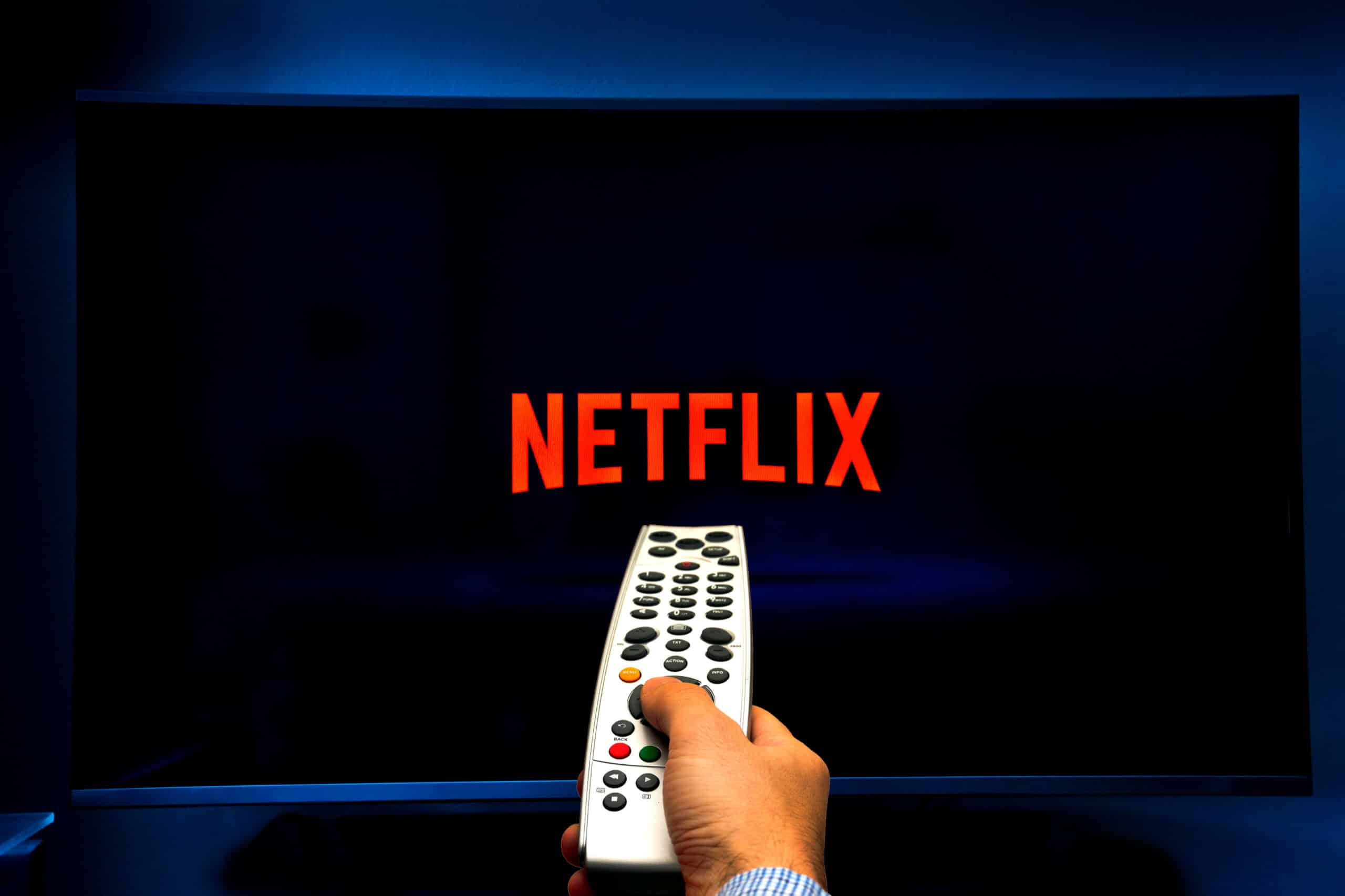 Male hand holding a remote control while watching Netflix on a TV screen