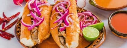 Guadalajara's torta ahogada: a carnitas-filled birote roll drowned in fiery chile de árbol sauce — the most food-unique dish in the 2026 World Cup host cities.