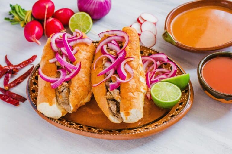 Guadalajara's torta ahogada: a carnitas-filled birote roll drowned in fiery chile de árbol sauce — the most food-unique dish in the 2026 World Cup host cities.