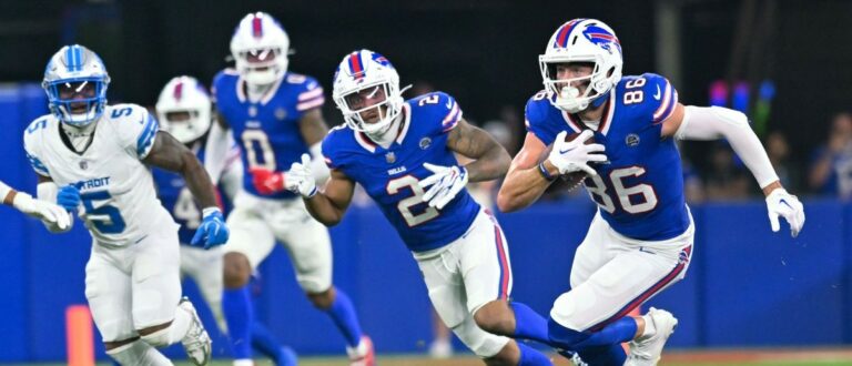 Buffalo Bills tight end Dalton Kincaid (86) runs for yards after making a catch with wide receiver DJ Moore (2) and Detroit Lions safety Christian Izien (5) in the first half at New Highmark Stadium. Mandatory Credit: Mark Konezny-Imagn Images