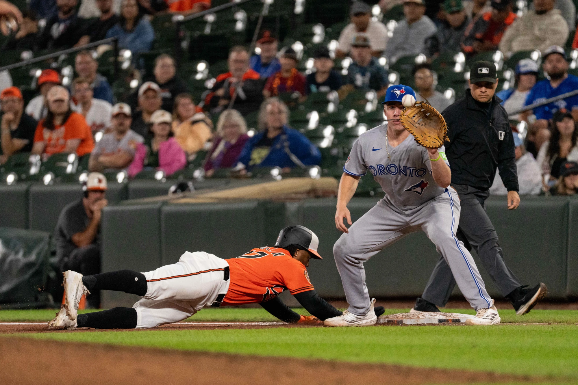 Sep 21, 2026; Baltimore, Maryland, USA; Baltimore Orioles outfielder Christian Franklin (27) dives to first base while Toronto Blue Jays designated hitter Sean Keys (20) attempts the tag during the eighth inning at Oriole Park at Camden Yards. 